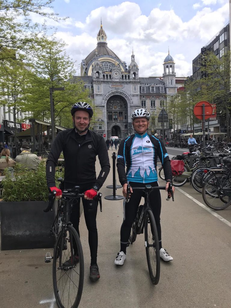 Twee wielrenners poseren voor een foto in een stedelijke omgeving